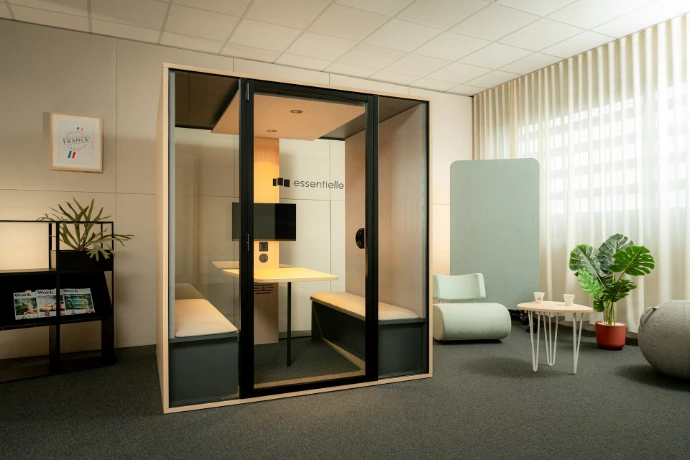 Modern office meeting pod with seating and desk.